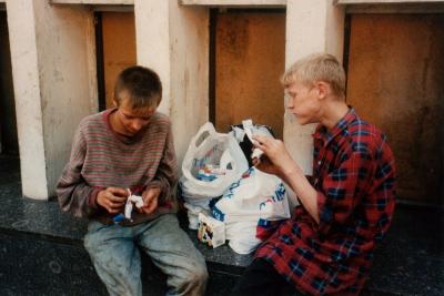 Dieses Bild zeigt zwei obdachlose, jugendliche Jungen, die irgendwelche Reste zu essen scheinen